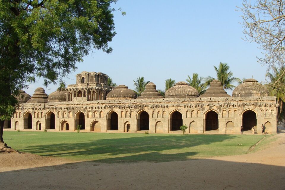 Zjawiskowa architektura w Hampi z majestatycznymi łukami i bujną zielenią w tle.