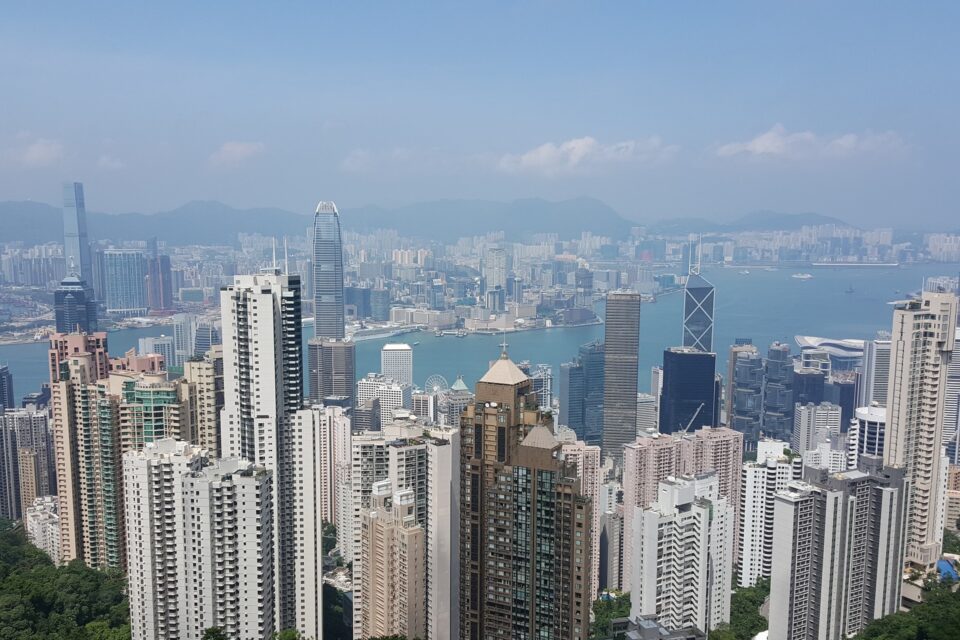Panorama Hongkongu z drapaczami chmur nad Portem Wiktorii i tłem górskim.