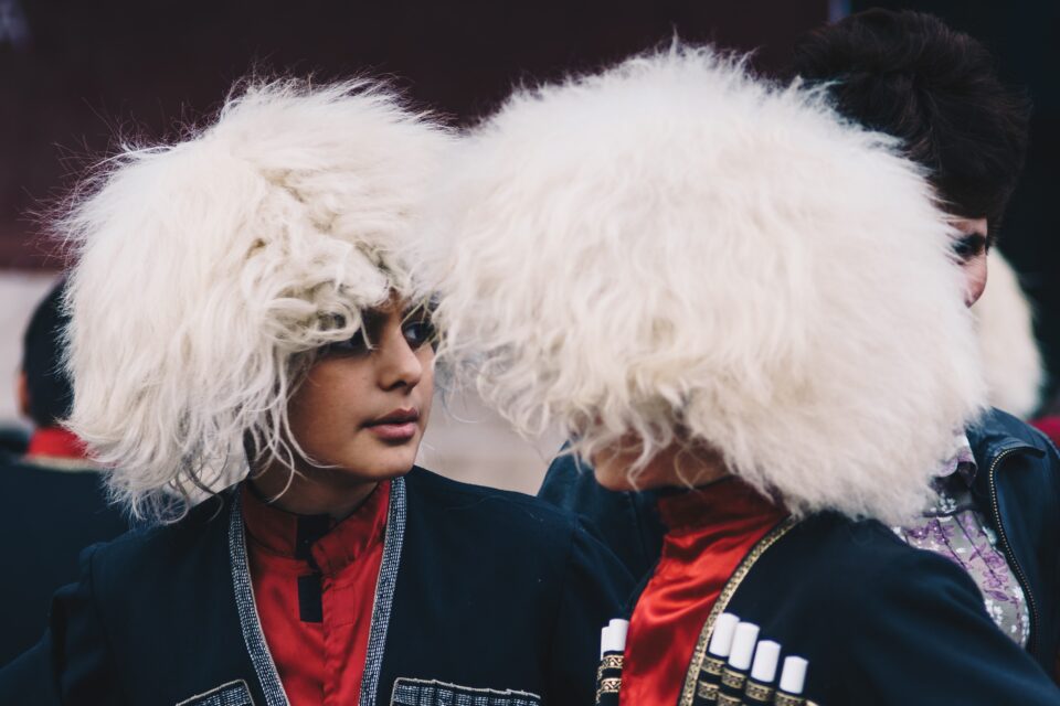 Chłopcy w tradycyjnych stroju kaukaskim na tle lokalnego festiwalu, pełni radości i energii.