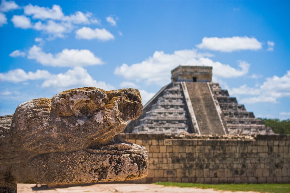 Kamienny wąż przed piramidą El Castillo w Chichen Itza pod błękitnym niebem.